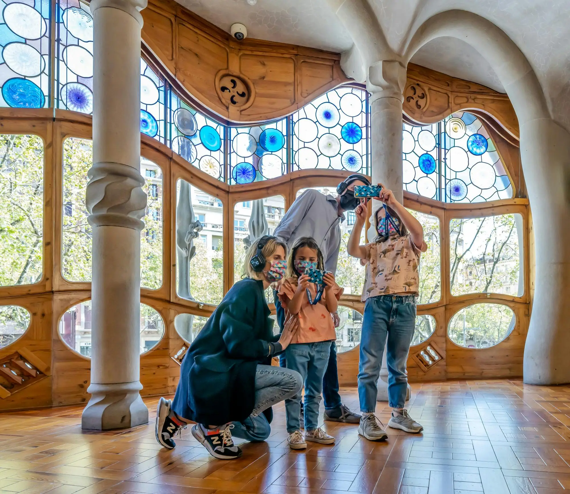 Family wearing masks uses audio guides inside Casa Batlló, Barcelona.